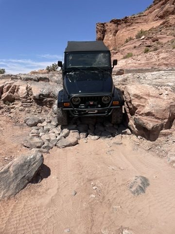 Black Jeep climbing a rocky desert trail