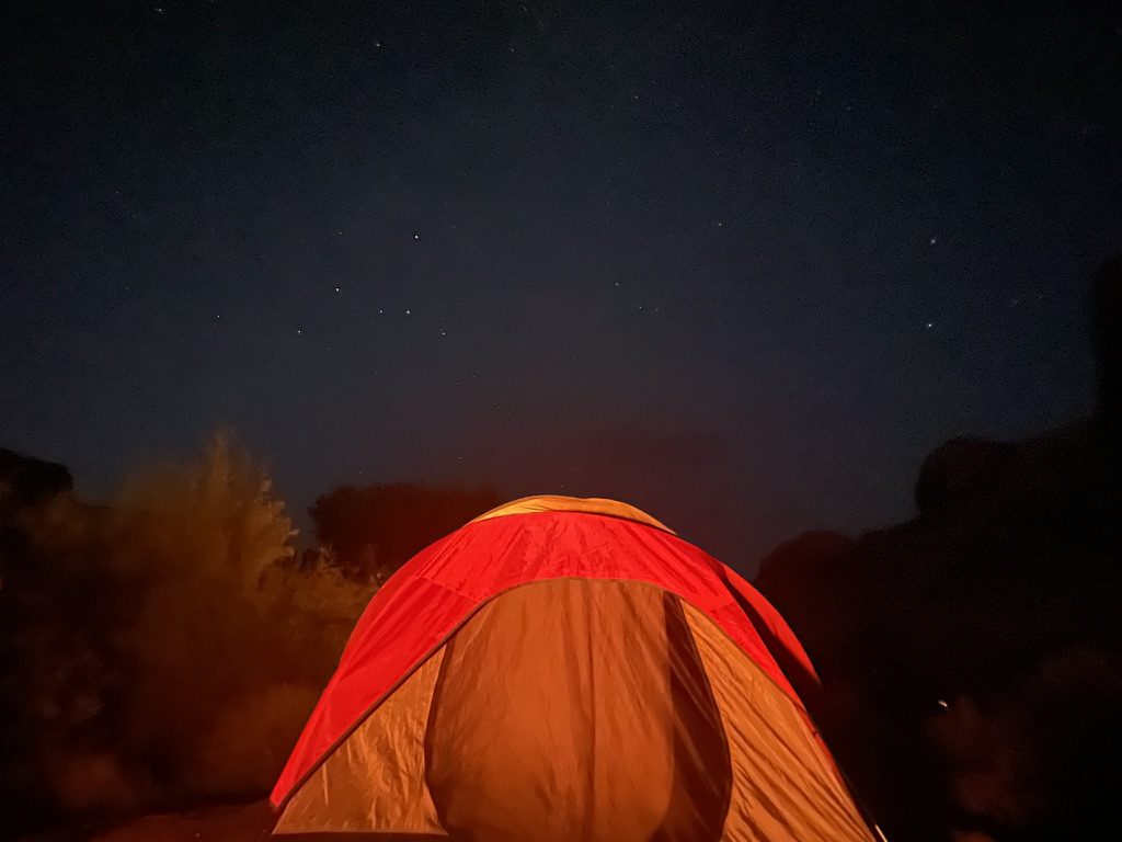 Glowing tent under a night sky full of stars